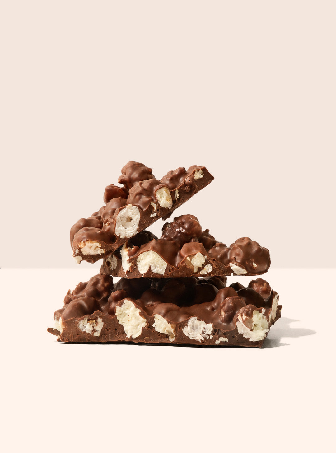 Milk chocolate slab combined with sweet and salty kettle corn. Stacked and presented on a beige background.